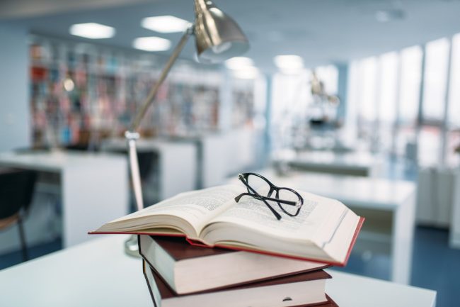 stack-of-books-and-glasses-on-table-in-library